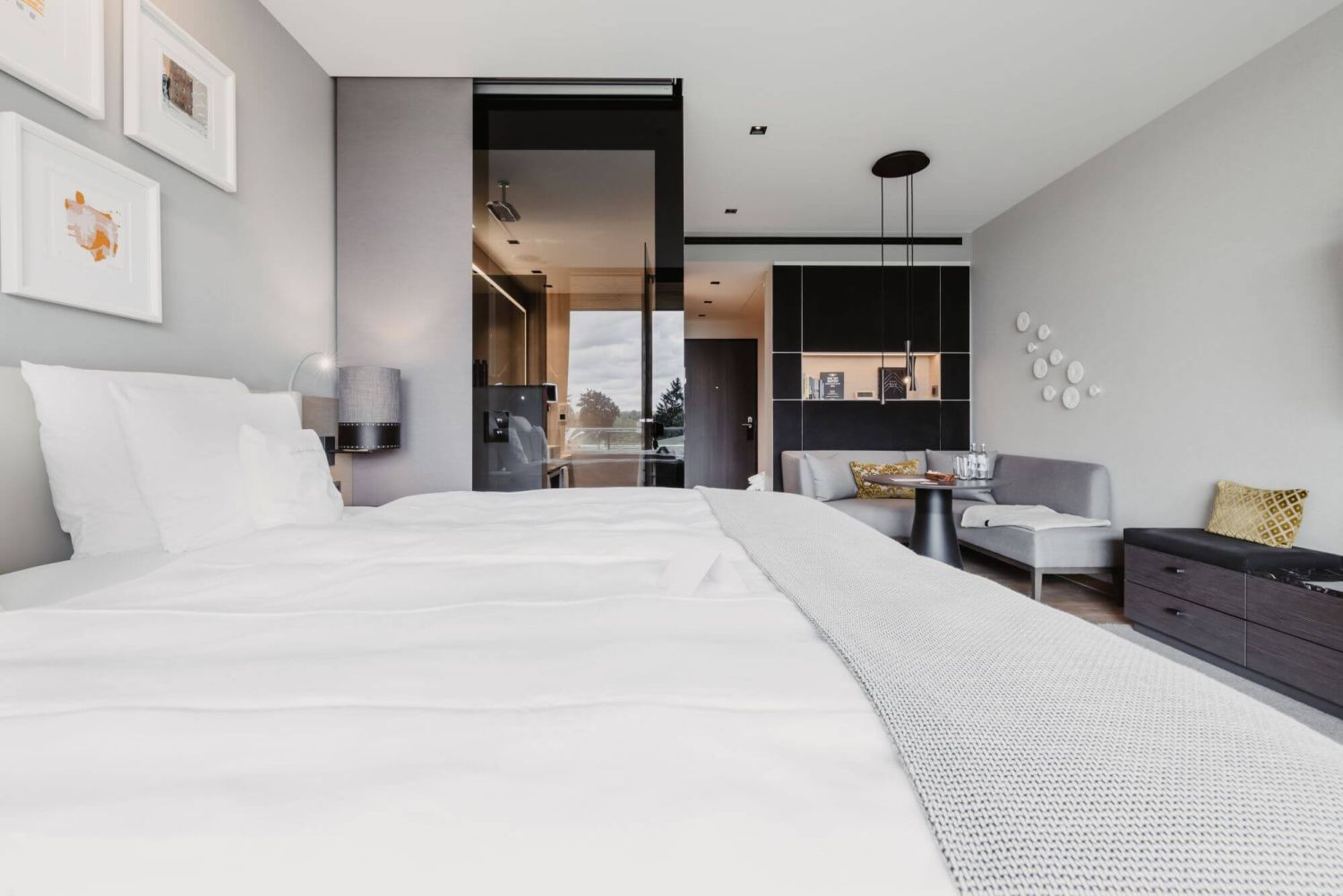 Lichtdurchflutetes Zimmer mit moderner Einrichtung, gemütlichem Bett und grauer Eckcouch