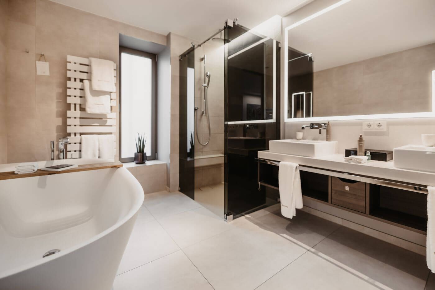 Modernes helles Badezimmer mit Badewanne, Dusche und großem beleuchteten Spiegel