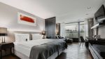 Großzügiges Zimmer mit gemütlichen Doppelbett an einer hellgrauen Wand mit einem abstrakten, roten Gemälde