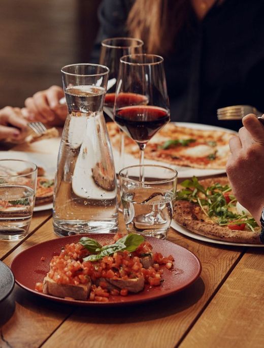 Gedeckter Tisch in der Pizzeria mit Pizzen, Vorspeisen und Rotwein