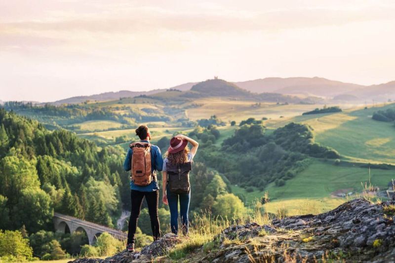 Zwei Wanderer stehen auf einem Berg und schauen über das Bergpanorama in die Ferne