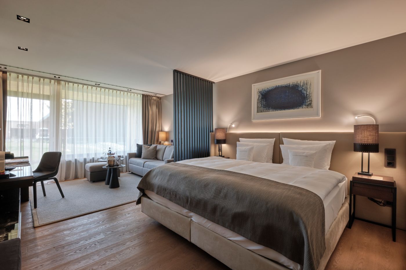 Blick auf ein Doppelbett neben dem Loungebereich mit Sofa und Beistelltisch im 5 Sterne Hotel im Schwarzwald