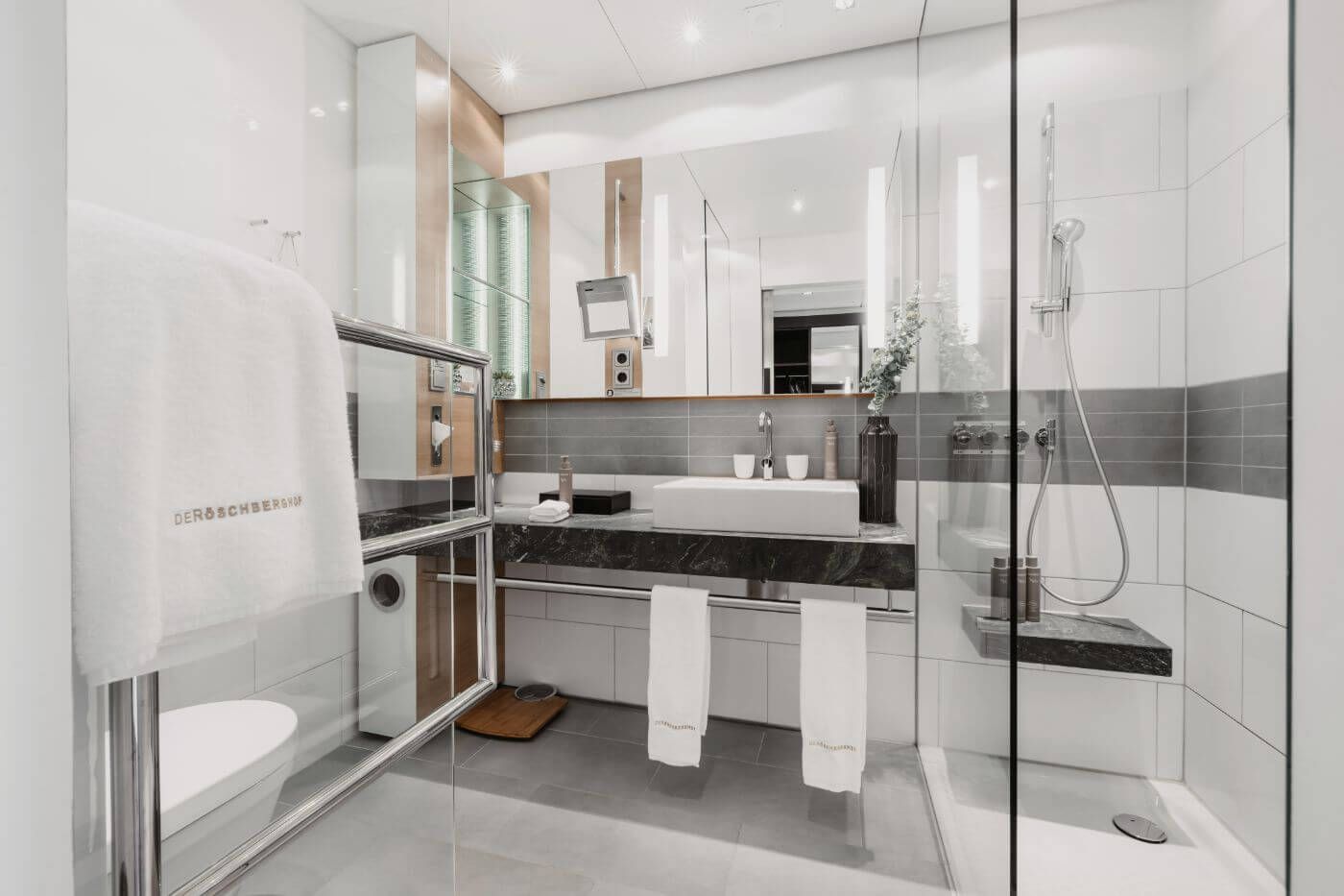 Helles Badezimmer mit Dusche und großem Spiegel über einem Waschbecken